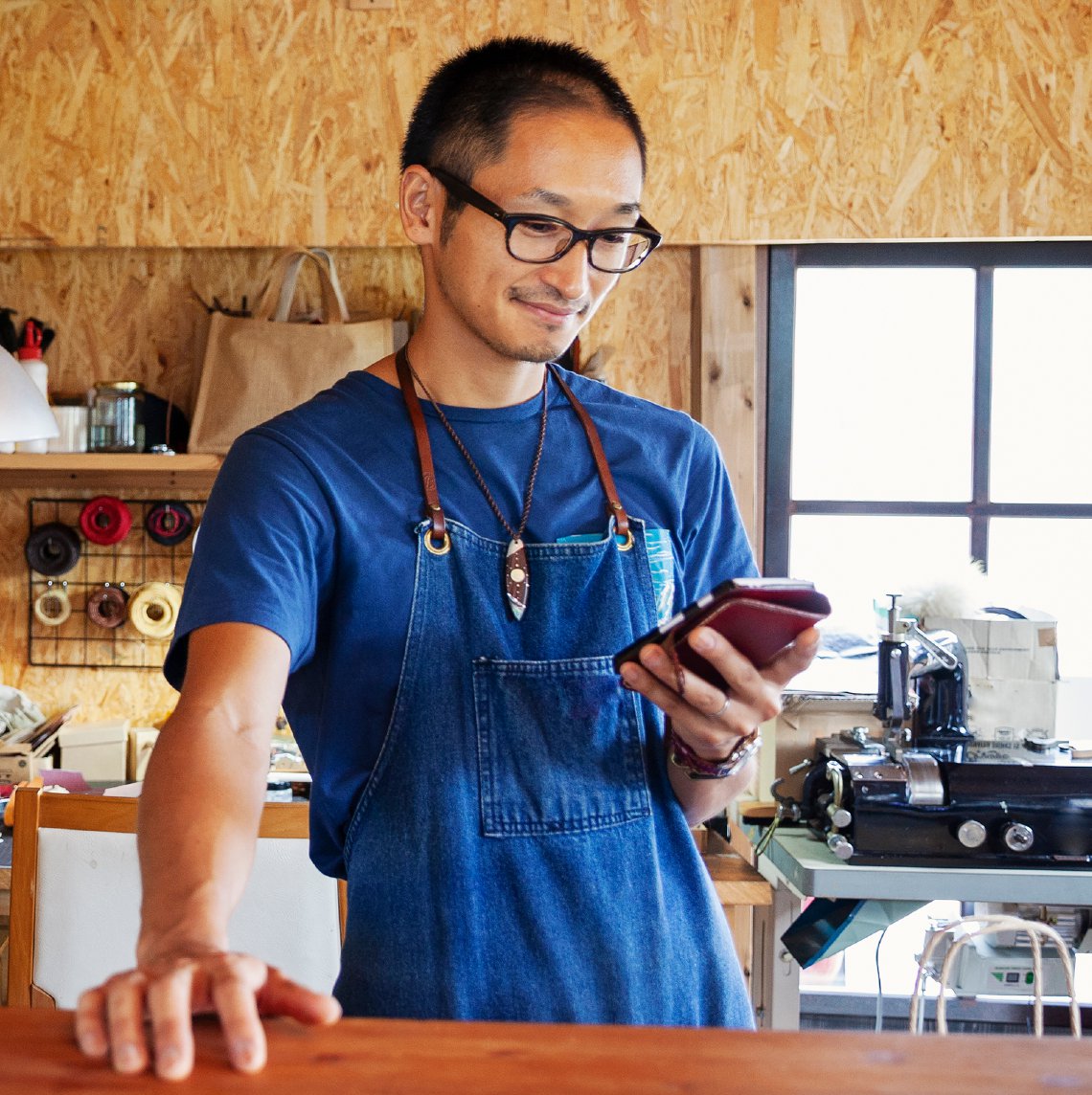 Japanese-American man on his phone in his shop.