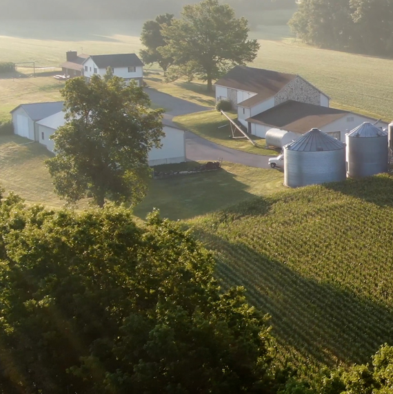 Photo of a farm field with buildings and small silos